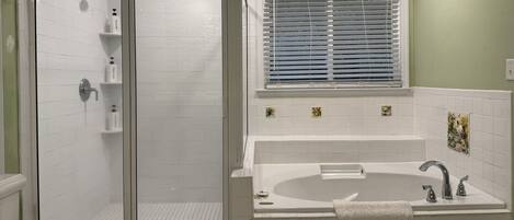 Un baño con cabina de ducha, bañera y ventana con persianas.