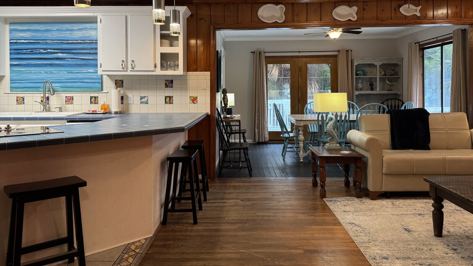 A kitchen with a large island, wooden flooring, and a dining area with a table and chairs.