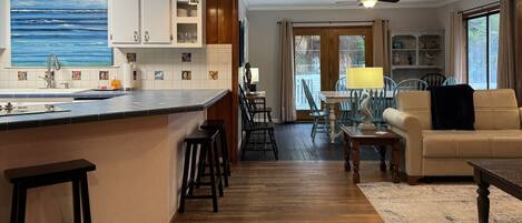 A kitchen with a large island, wooden flooring, and a dining area with a table and chairs.