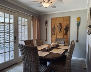 A dining area with a round table, wicker chairs, and decorative wall art. - Two Fish -south beach, lots of amenities (Tybee Island)