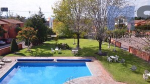 Ein rechteckiger Pool mit einem kleinen runden Bereich, umgeben von einer Ziegelterrasse.