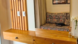 A modern bedroom with a wooden vanity, a large mirror, a patterned sofa, and a view of the sea through the window. - Chalet near the beach, with kitchen and balcony with hammock. Couples and families with children (São Miguel do Gostoso)