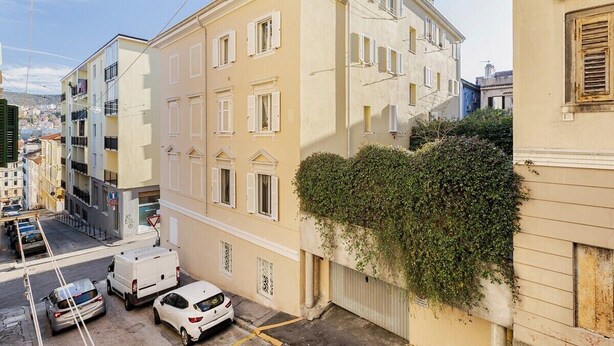 A narrow urban street with a yellow building featuring multiple windows and balconies. - MV - Three-room apartment, covered garage 15 minutes from downtown (Trieste)