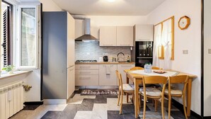 A compact kitchen with a dining area, featuring a stove, oven, and refrigerator. - MV - Three-room apartment, covered garage 15 minutes from downtown (Trieste)