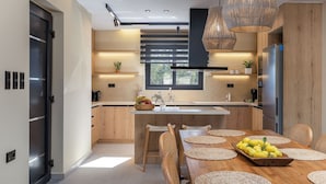Een moderne keuken met houten kastjes, een centraal eiland en een eethoek met een houten tafel en stoelen.