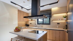 Een moderne keuken met houten kastjes, een centraal eiland met krukken, een ingebouwde kookplaat en een raam voor natuurlijk licht.