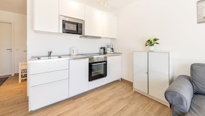 A modern kitchen with white cabinets, a microwave, an oven, and a coffee maker. - Ferienresidenz Hinterzarten FEWO H2 (Hinterzarten)