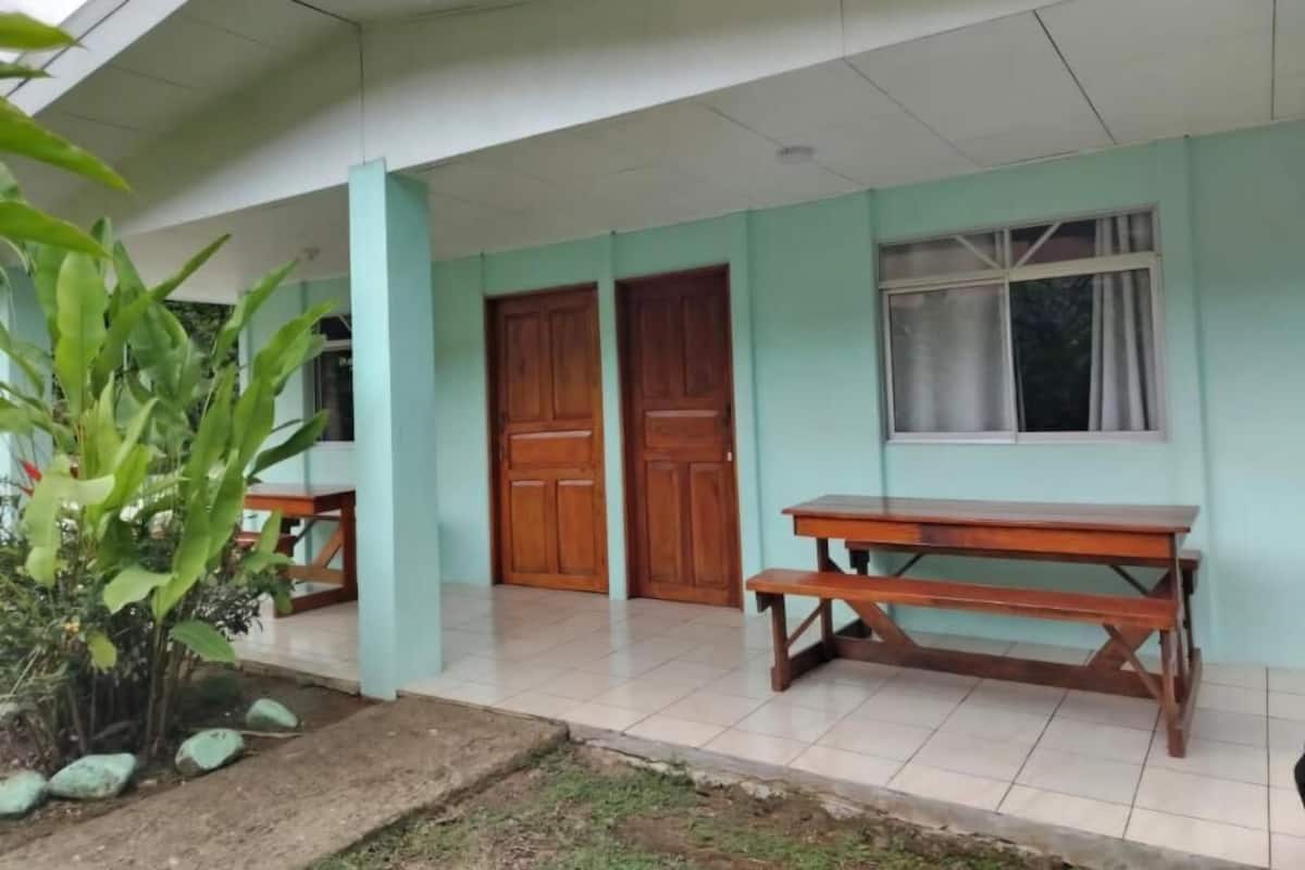 Un edificio con un porche cubierto, un banco de madera y una puerta.