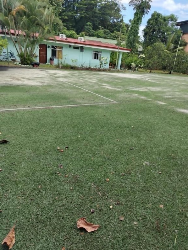 A grassy outdoor area with a building in the background. - Villas Cabinas Hidalgos (Ciudad Cortes)