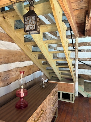 Una scala in legno con un lanterna e un vaso rosso su un comò di legno.