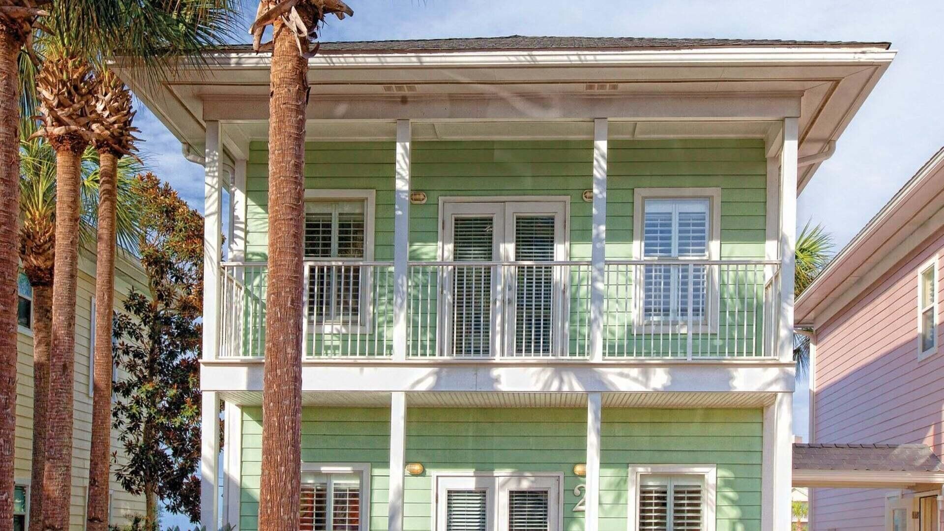 A two-story house with a balcony, green siding, and white trim.
