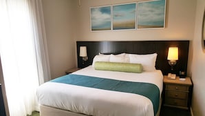 Ein Hotelzimmer mit einem großen Bett, zwei Nachttischen, einer Lampe und drei Bildern an der Wand.