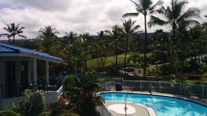 Une piscine entourée de palmiers et un bâtiment avec un toit bleu.