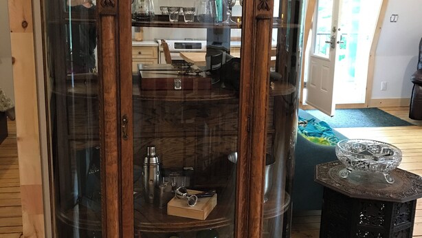 Un mueble de madera con puertas de vidrio que contiene diversos objetos.