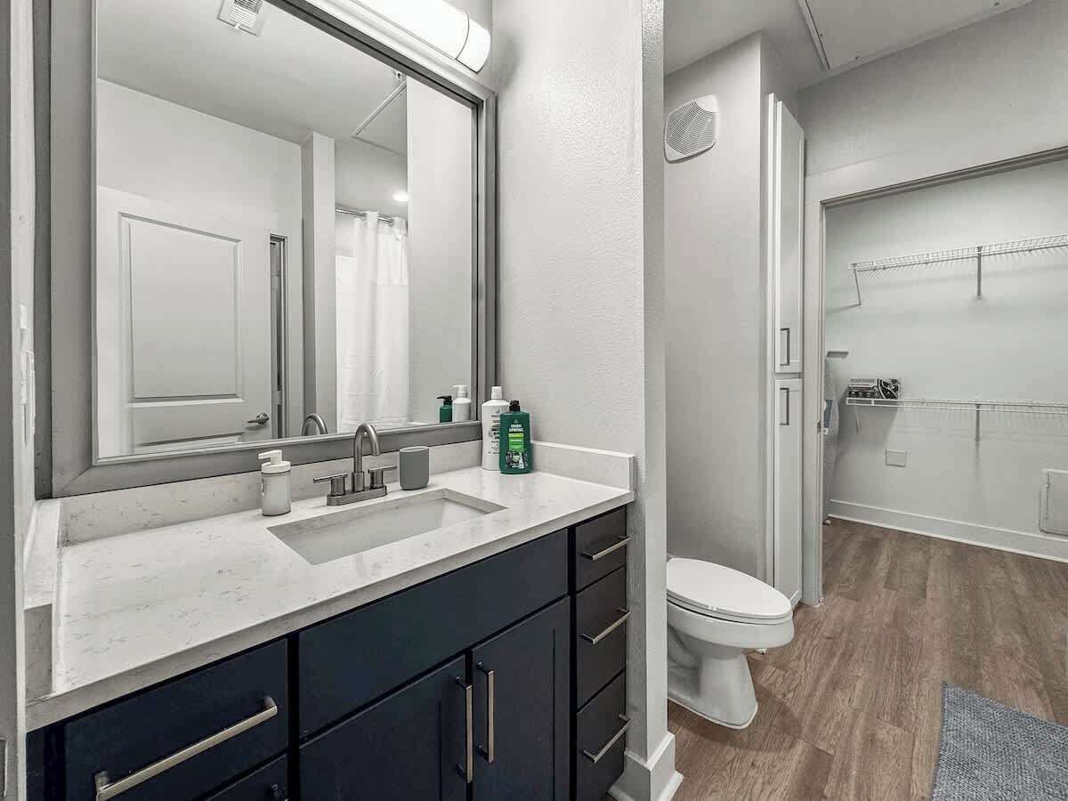 Un baño moderno con lavamanos doble, gabinetes oscuros, inodoro y zona de ducha.