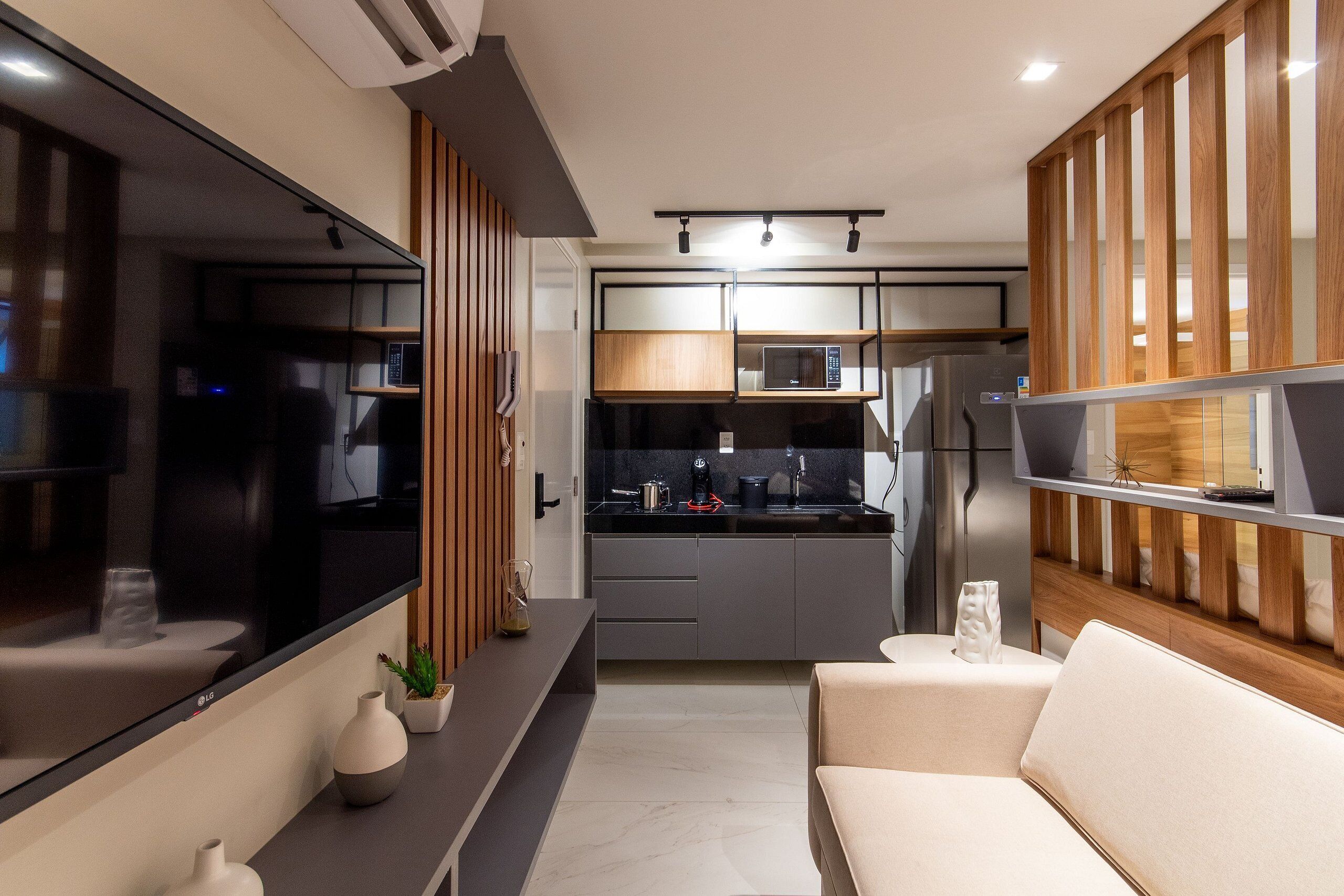 A modern kitchen with a microwave, refrigerator, and wooden paneling.