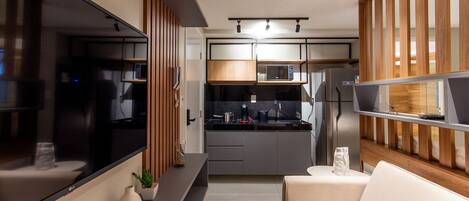 A modern kitchen with a microwave, refrigerator, and wooden paneling.