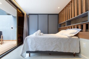 Een moderne slaapkamer met een bed, inbouw houten planken en een schuifdeur naar een balkon.