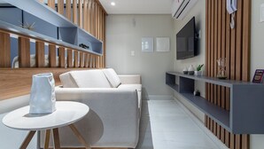 A modern living room with a sofa, a round table, and built-in shelves. - Unity Cabo Branco Seafront by Carpediem (João Pessoa)