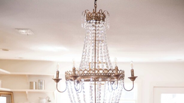 A dining area with a chandelier, white chairs, a wooden table, and a vase of pink flowers. - NEW | Round Top Girls' Getaway | 2 BR w/ Fire Pit (Burton)