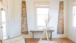 Ein geräumiger Raum mit Holzboden, einem großen Fenster, einem Holzstuhl, einem kleinen runden Tisch und einer dekorativen Wandgestalt.