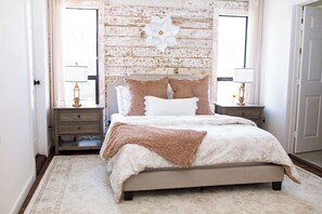 A bedroom with a bed, nightstands, a decorative wall, and a window. - Charming 2BR + Firepit | Minutes to Town + Shops (Burton)