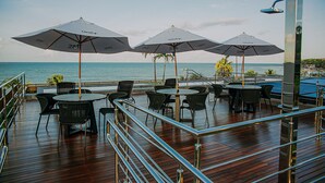 Una terraza con mobiliario exterior, sombrillas y vista al mar.