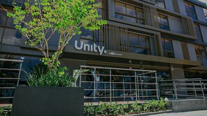 Een modern gebouw met het bordje 'Unity' en een boom ervoor.