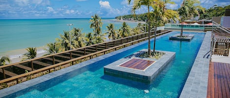 A pool with a wooden deck and a view of the beach.
