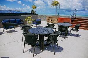 Eine Terrasse im Freien mit einem runden Tisch, Stühlen, einem blauen Sofa und Blick aufs Meer.