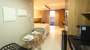 Hotelkamer met een bed, een eettafel met stoelen, een magnetron en uitzicht op de stad.