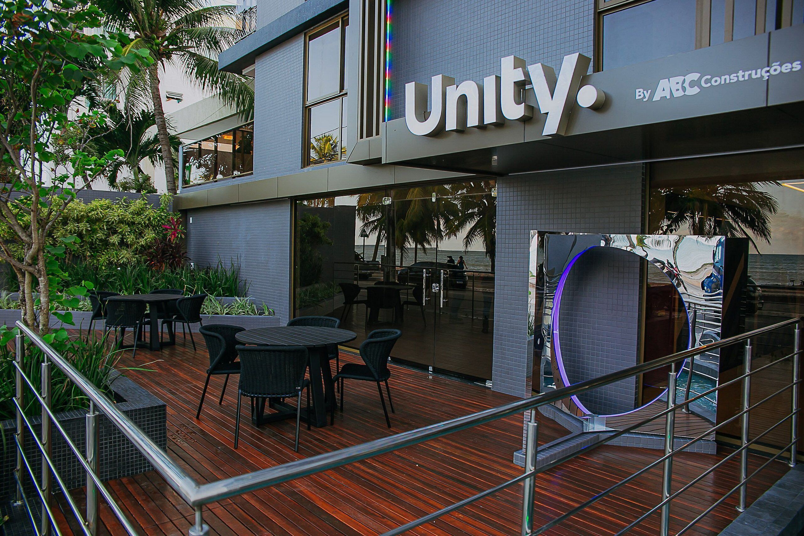 Um edifício moderno com a placa 'Unity', área de estar externa e entrada de vidro.