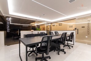 A modern conference room with a long table, black office chairs, and glass partitions. - Unity #222 a Few Steps From the Beach by Carpediem (João Pessoa)