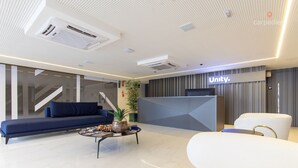 A modern hotel lobby with a reception desk, seating area, and a staircase. - Unity #222 a Few Steps From the Beach by Carpediem (João Pessoa)