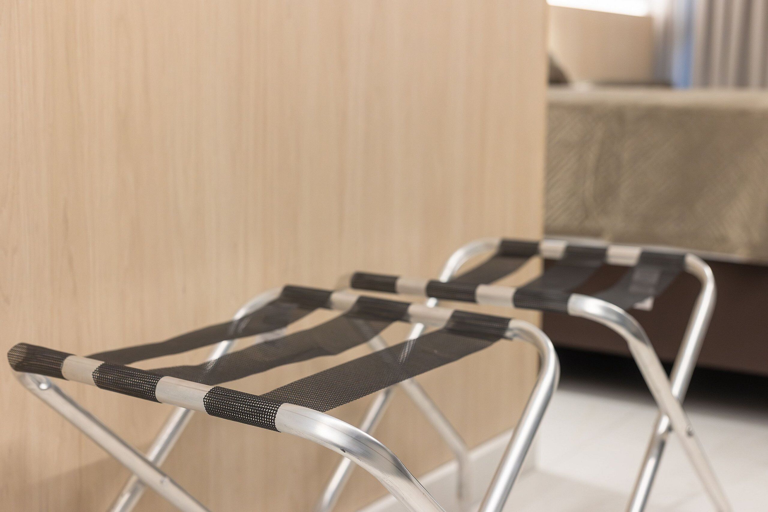 Dos sillas con estructura metálica y asientos y respaldos de tela blanca y negra, ubicadas en una habitación con una pared de madera y un banco acolchado al fondo.