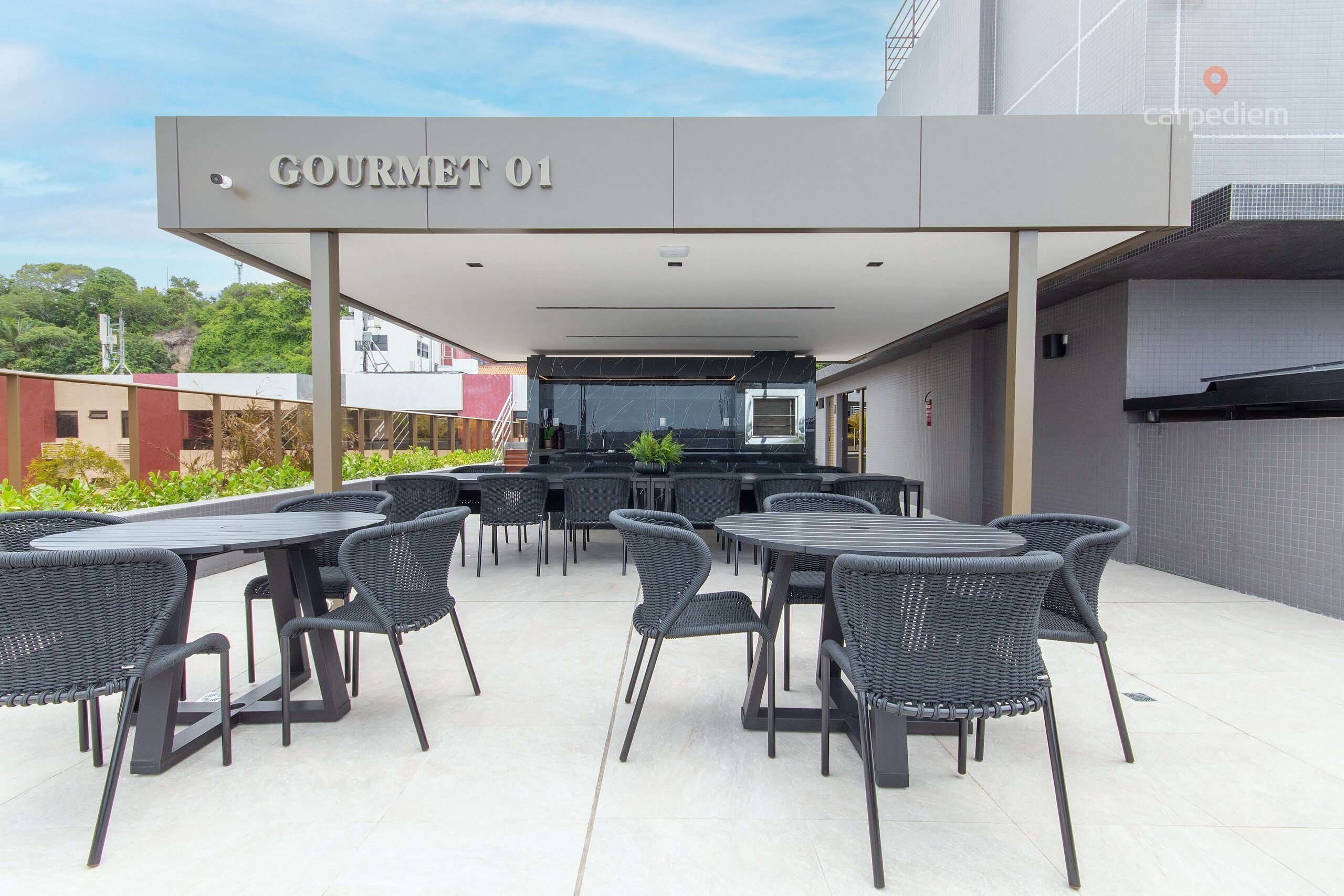 An outdoor dining area with a covered seating arrangement, a bar, and a sign reading 'GOURMET 01'.
