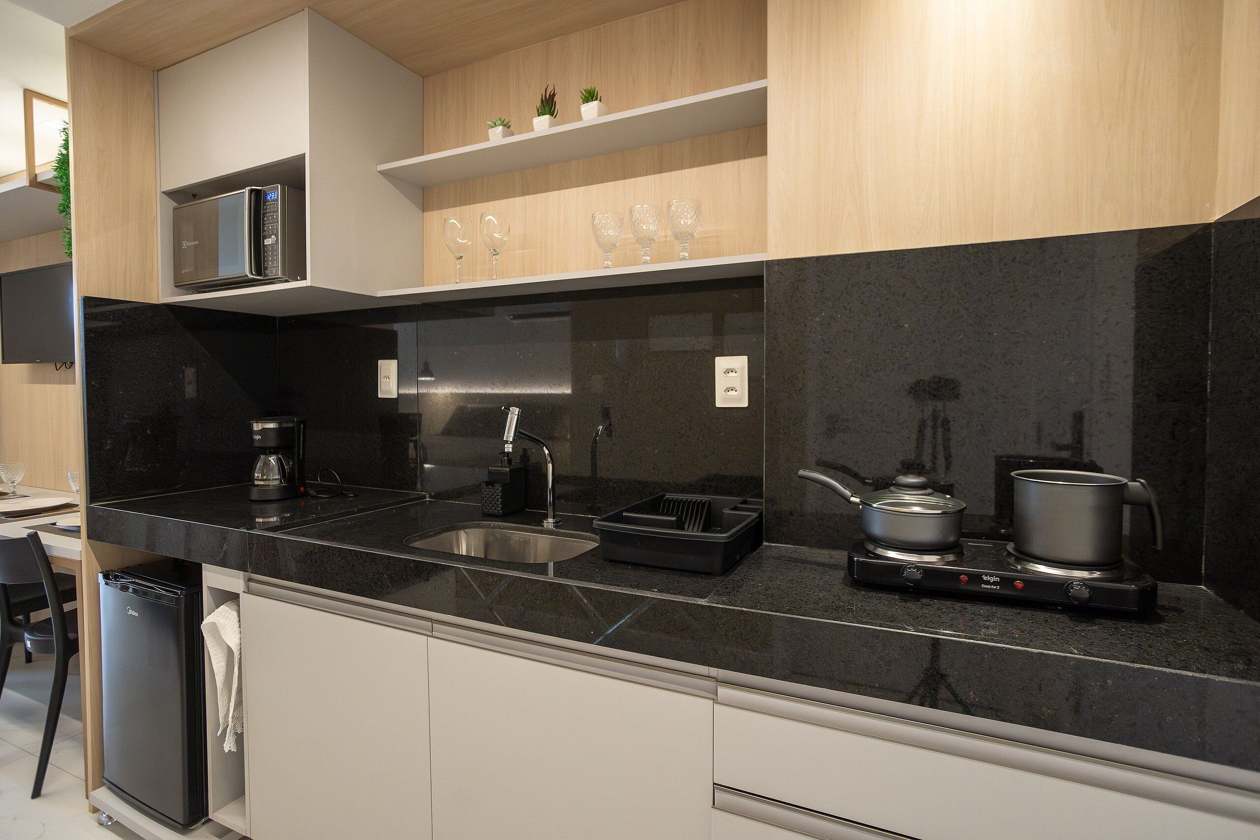 Una cucina moderna con piano di lavoro nero, elettrodomestici in acciaio inossidabile e forno a microonde integrato.