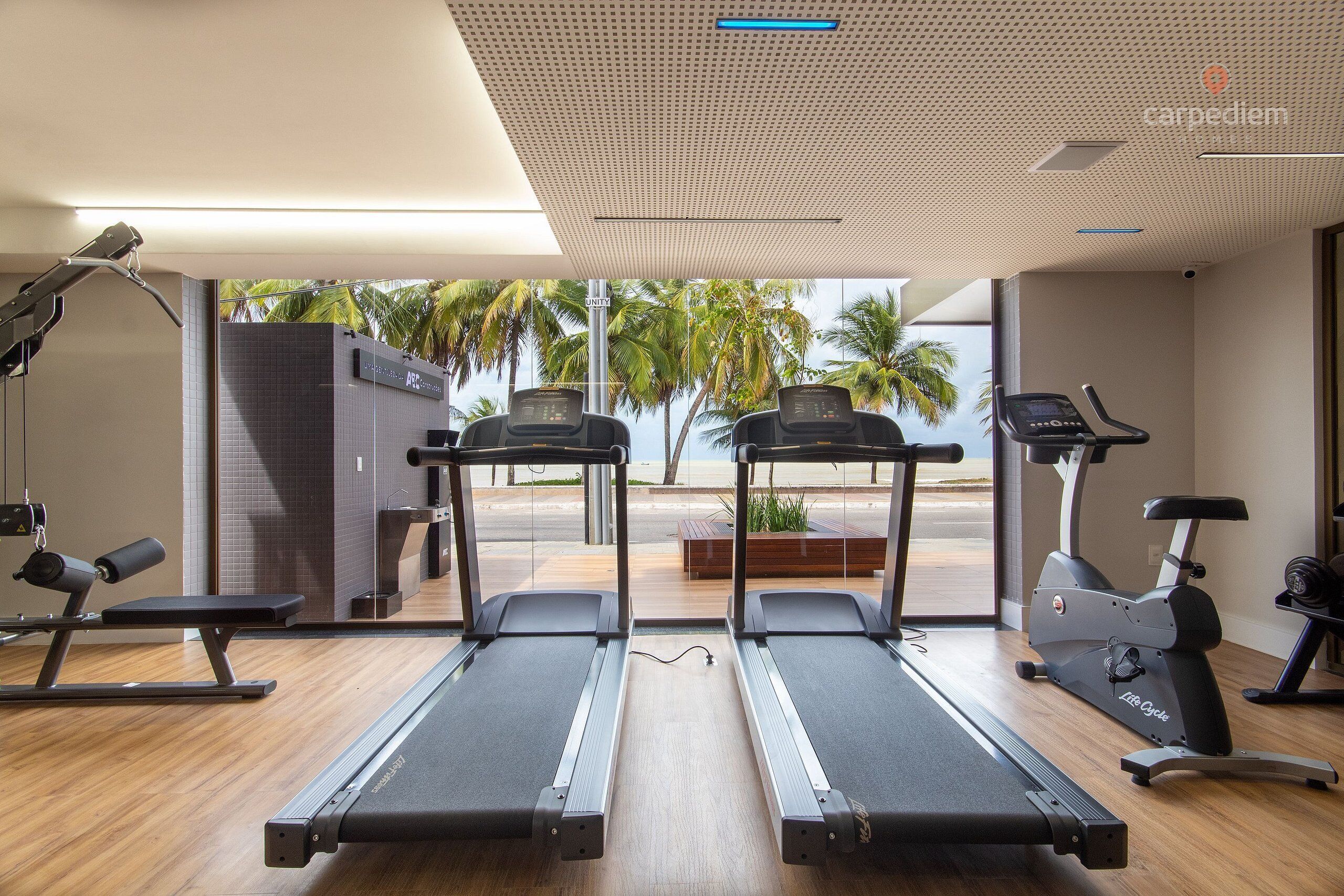 Ein Fitnessraum mit Laufbändern, einem Ergometer und einer Bank.