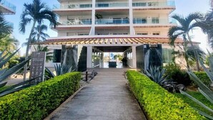 Ein mehrstöckiges Hotel mit Innenhof, umgeben von Palmen und gepflegten Hecken.