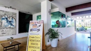 Ein modernes Interieur mit Holzboden, Couchtisch, Topfpflanze und einem Schild, das ein Café bewirbt.