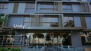 Een modern gebouw met een bord waarop 'Unity' staat. Het heeft een meerlaags gebouw met grote ramen, een overdekte ingang en een waterpartij ervoor.
