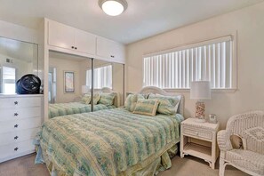 Une chambre à coucher avec un lit, une commode, une table de chevet et une chaise.