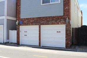 Un bâtiment à deux étages, doté d’une façade en briques et de deux portes de garage blanches.