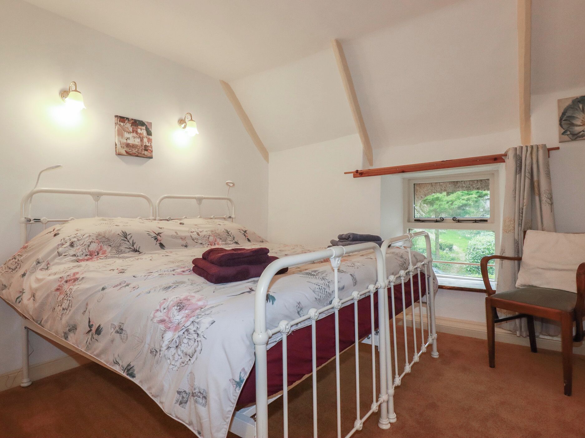 Quarto com cama, janela com vista, cadeira e luminárias na parede.