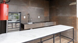 A modern kitchen with a marble countertop, a sink, and a fire extinguisher. - Vivendas #404 - Apto em Cabo Branco by Carpediem (João Pessoa)