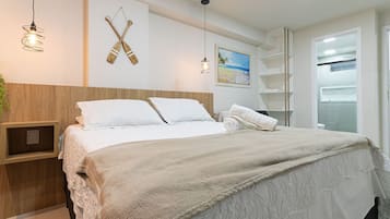 Una cama bien hecha con un edredón mullido, un cabecero de madera y una estantería con una pequeña planta.