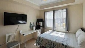 A bedroom with a bed, a desk, a chair, a TV, and a window with blinds. - Cozy Studio – Free Bikes – 1 Mi to Beach (Bonita Springs)