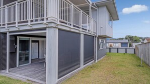 A modern two-story house with a balcony, a garage, and a grassy yard. - Soleil Studio - Whangamata Self-contained Unit (Whangamata)