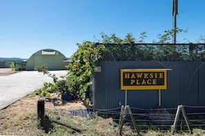 A sign reading "HAWKSIE PLACE" with a fenced area and a green building in the background.