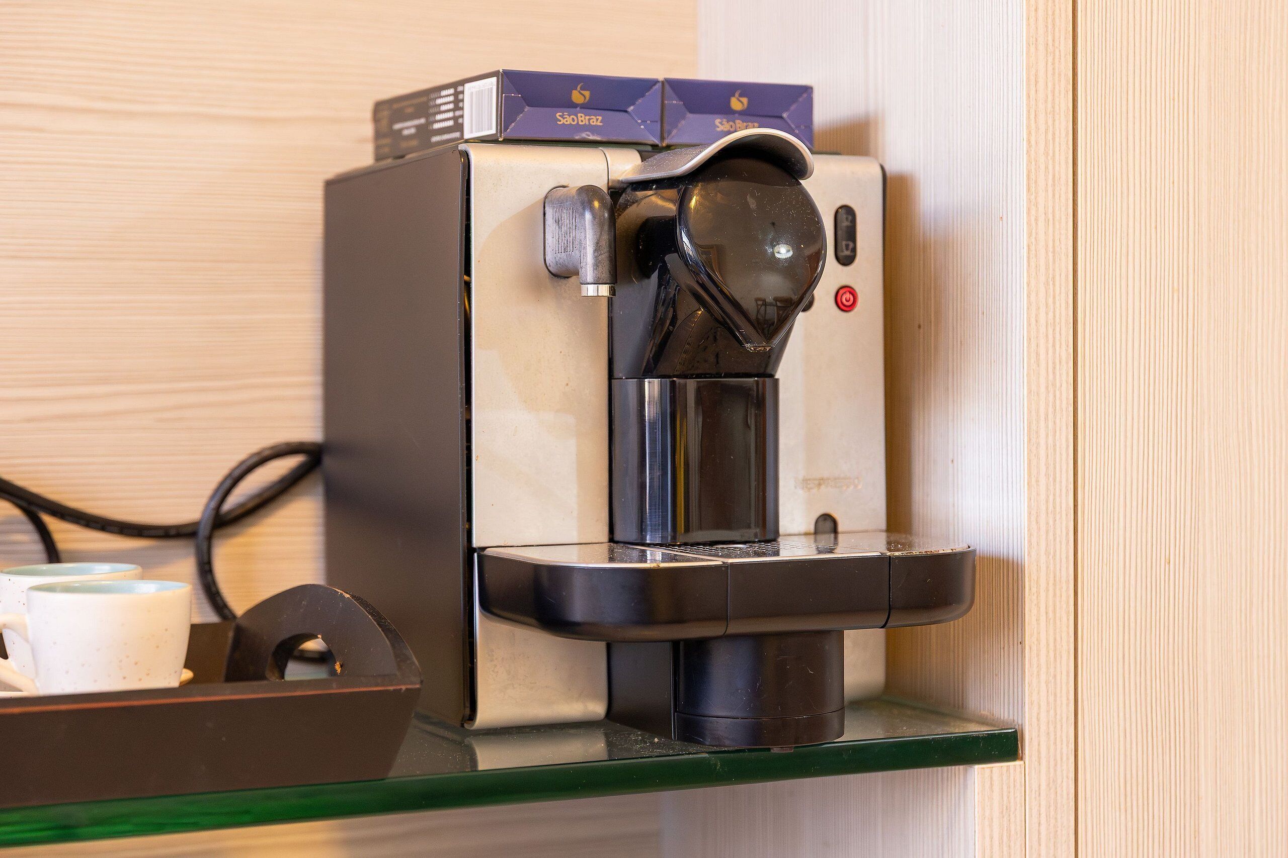 A coffee machine with a cup holder, a control panel, and a branded box on top.